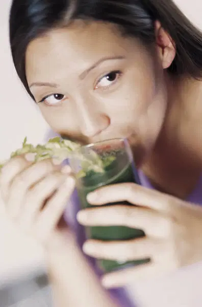 beautiful black woman drinking a green concoction